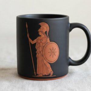 Mug noir mat à décor cuivre : la déesse Athéna casquée, tenant lance et bouclier étoilé.